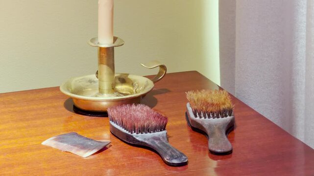 Vintage hairbrushes and a comb sit on a polished table in Pushkin, Saint Petersburg. Soft light highlights the daily items. The quiet display evokes a nostalgic and cozy feeling.