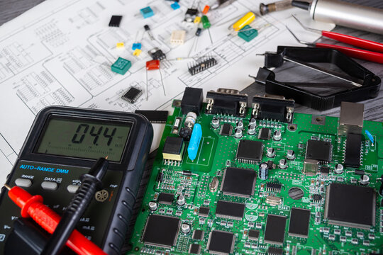 Working on a circuit board with multimeter and various components on a work table