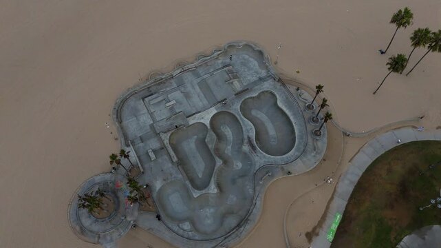Los Angeles, United States - 03 September 2026: Aerial view of the Venice Beach Skatepark with concrete bowls and ramps surrounded by sandy beach.