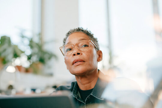 Thoughtful Senior  Woman with Glasses Looking Up in Bright Home Interior
