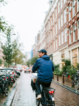 Food Delivery Courier Cycling with Insulated Bag Through Rainy City Street