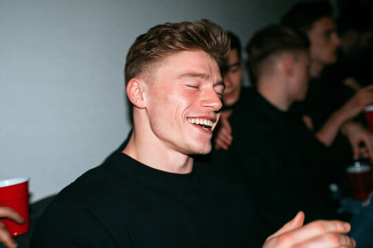 Young Man Laughing at House Party with Direct Flash Photography Aesthetic