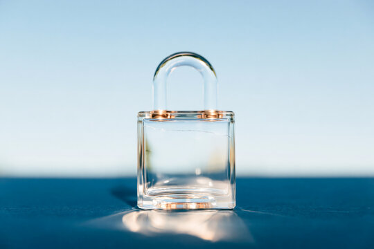 Cracked Transparent Glass Padlock on Blue Surface as Security and Data Breach Concept