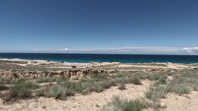 Forward tracking shot along arid coastal landscape and ocean