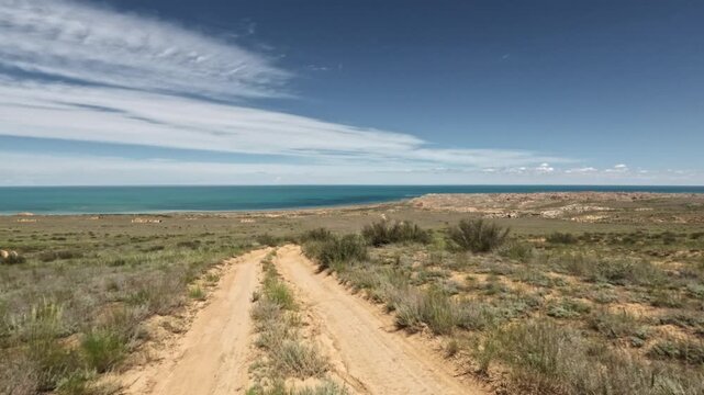 Dirt road descending toward blue water in open landscape