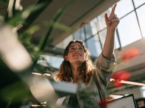 Smiling woman pointing upwards in a bright modern office