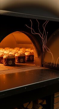 Freshly baked panettone cakes baking inside a glowing warm stone bakery oven
