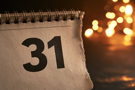 Close-up of a calendar page showing the number thirty-one, illuminated by warm, festive bokeh lights in the background, symbolizing the end of the year or a significant date.