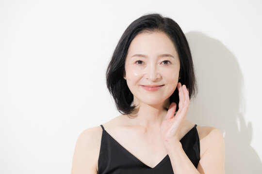 美しい肌と自然な表情が印象的な50代女性のビューティーポートレートカメラ目線の真剣な表情　スキンケアとエイジングケアのイメージ