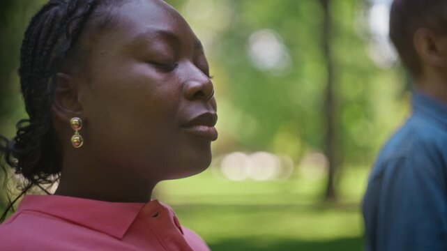 African American young woman placing hands on chest and breathing deeply during outdoor therapy session. Footage ideal for mental health campaigns and wellness advertising