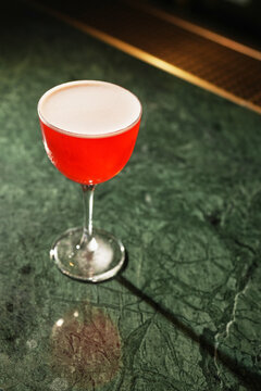 Red Alcoholic Sour Cocktail with Foam in Stemmed Glass Close Up
