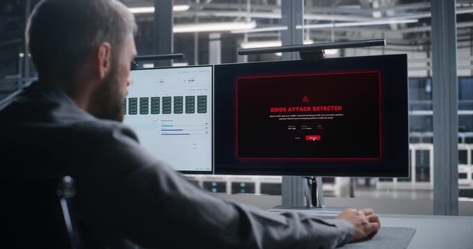 Network Operations Engineer Responds to DDoS Attack Across Data Center Infrastructure, Analyzing System Activity on Dual Monitors to Support Threat Mitigation, Network Security, and Continuity.