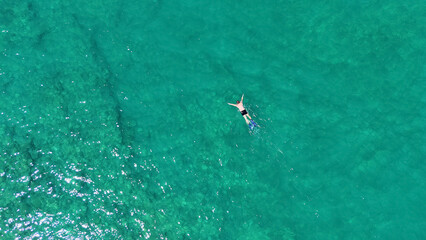 A man in a mask and flippers is swimming in clear, transparent water at the sea © Павел Чигирь