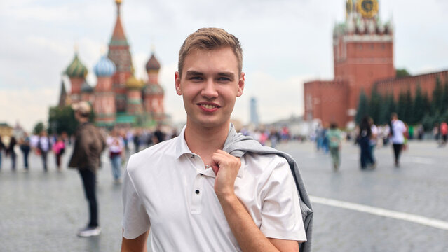 Young man with light hair in white clothes standing on Red Square in Moscow, Russia. Famous historical landmark travel tourism concept.