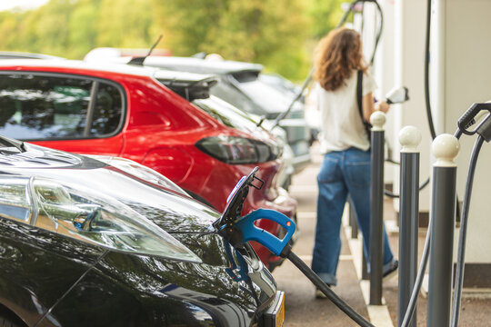 Electric vehicles charging at modern station with cables, eco friendly cars, sustainable transport and green urban mobility lifestyle