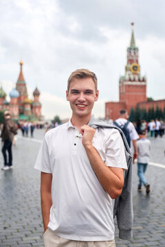 Young man with light hair in white clothes standing on Red Square Moscow, Russia. Famous historical landmark travel tourism concept.