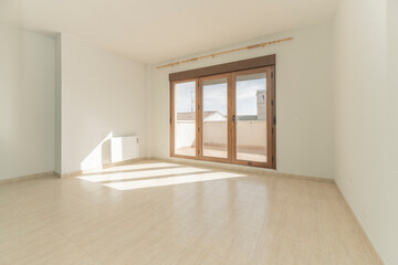 Obraz premium Empty sunlit room with wooden triple French doors opening to a rooftop terrace with church tower view.