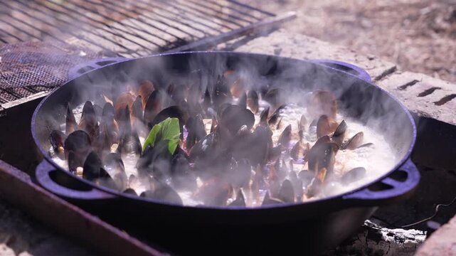 Traditional cooking. Mussels prepared in a large cauldron over a campfire