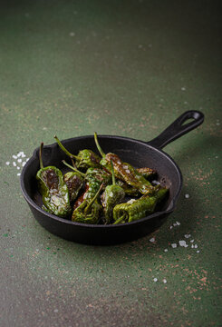 Padron peppers fried cast iron skillet sea salt dark green background Spanish appetizer