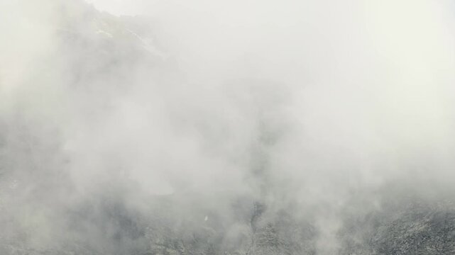 Clouds drifting across rocky mountain slope