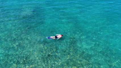 A man in a mask and flippers is swimming in clear, transparent water at the sea © Павел Чигирь