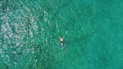 A man in a mask and flippers is swimming in clear, transparent water at the sea © Павел Чигирь