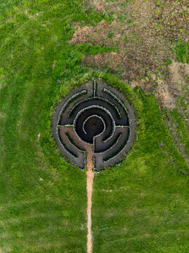 Aerial view of a circular stone labyrinth set within a lush green field in Iceland.