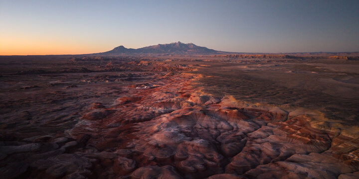 Aerial view of the Bentonite Hills near Hanksville, Utah, with the Mars Desert Research Station visible amid colorful Mars-like terrain and the Henry Mountains in the distance.