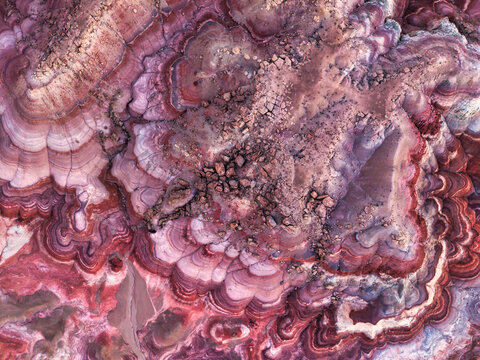 Aerial view of Hanksville Bentonite Hills showing vibrant purple, red, and white clay layers with intricate erosion patterns and rocky outcrops Hanksville, Utah, United States.
