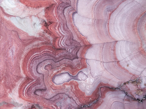 Aerial view of the colorful, striated clay layers of the Hanksville Bentonite Hills, showcasing intricate geological patterns and vibrant red bands in Hanksville, Utah, United States.