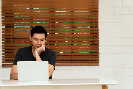 Young man focused on a laptop at a home workspace, representing remote work, productivity, technology, concentration, and a modern digital lifestyle