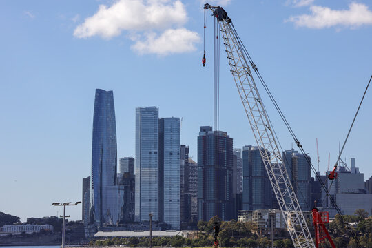 View of a large lattice boom crane set against the modern city skyline, highlighting heavy construction and waterfront industry in Barangaroo, New South Wales, Australia.