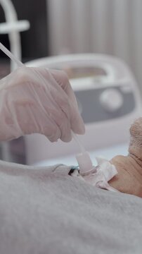 Close-up Hand of nurse suctions mucus from a tube in the throat of a patient who had a tracheostomy and is recovering at home