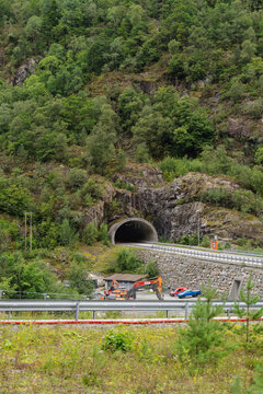 August 16, 2026, Saudasj&oslash;en, Norway - Road tunnel entrance in a forested mountain with construction vehicles