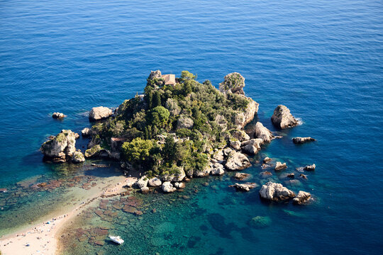 Aerial view of the stunning Isola Bella in Taormina, Sicily, showcasing its rocky shores, verdant vegetation, and crystal-clear turquoise waters
