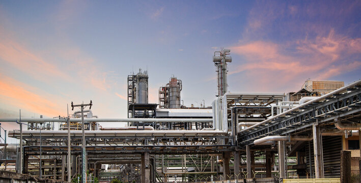 Petrochemical plant with distillation towers and pipe racks against bright sky.Large oil and gas refining facility with complex pipeline infrastructure
