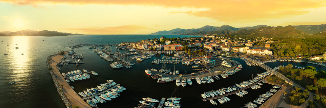 Iconic Saint Florent Corsica France aerial drone panorama sunrise golden hour marina yachts glowing boats pastel town mountains landscape travel destination high resolution world print