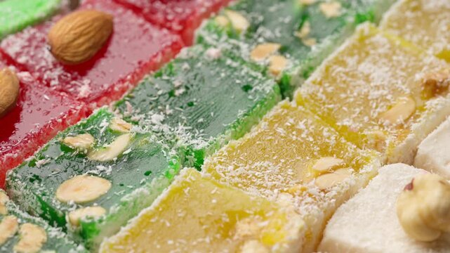 Assorted colorful Turkish delight sweets with nuts and coconut flakes rotating slowly close up. Rahat Lokum	
