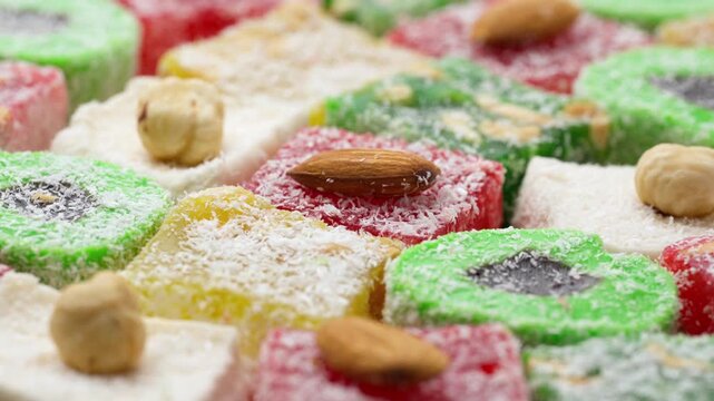 Assorted colorful Turkish delight sweets with nuts and coconut flakes rotating slowly close up. Rahat Lokum	
