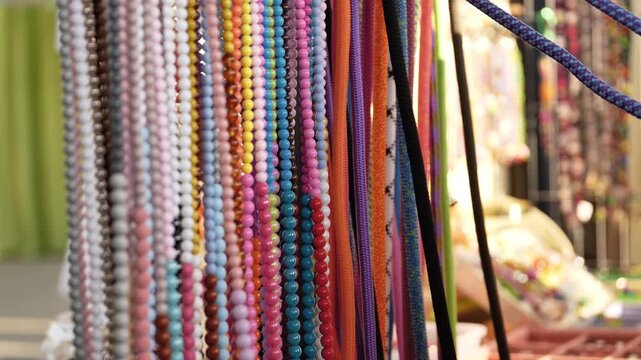 Hand choosing colorful beaded necklaces and ropes at a vibrant market stall