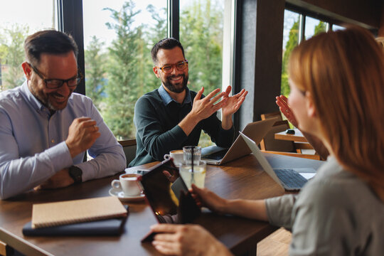 Business colleagues laughing and collaborating during a casual meeting at a bright modern office cafe