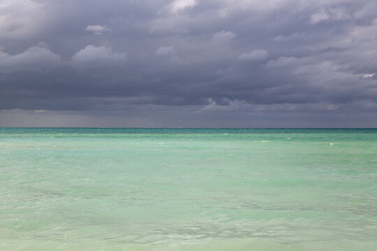 View of the turquoise waters of the Caribbean Sea under a dramatic sky with dark storm clouds in Cayo Coco, Ciego de Avila, Cuba.