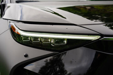 Modern LED headlight and glossy body detail of a black luxury vehicle © heerim studio
