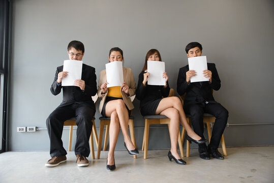 Business professionals in group holding documents and paperwork, showing team, employment, and recruitment concept in office workplace, with corporate colleagues sitting together and copy space.
