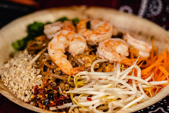 Pad Thai dish, with shrimp, stir-fried rice noodles, bean sprouts, crushed peanuts and vegetables, served in a bamboo dish