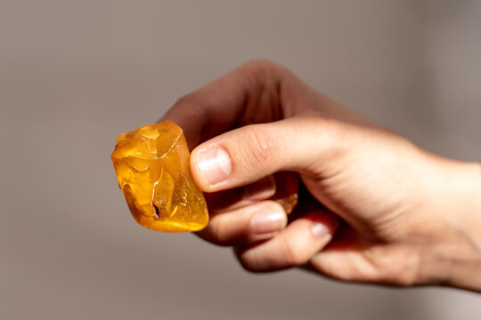 Big piece of amber in the hand of a girl illuminated by sunlight