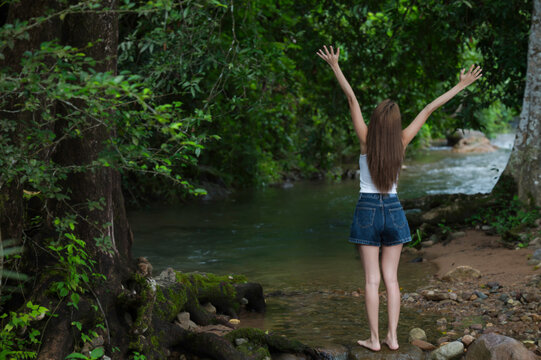 Young Woman Relaxing in Nature Beside a Forest Stream