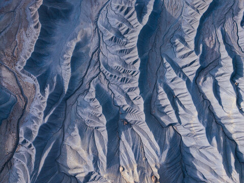 Aerial view of the eroded badlands of Caineville Mesa, featuring intricate ridges, deep gullies, and textured desert terrain in Wayne County, Utah, United States.