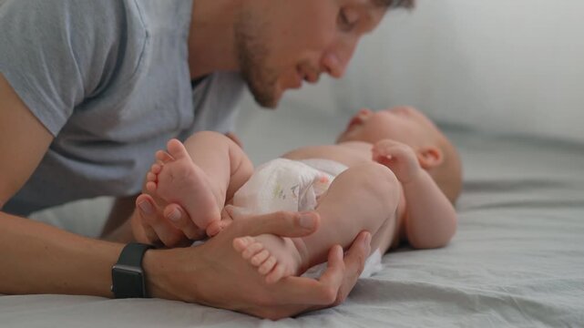 Father kissing belly and feet of his three month old baby son. Slow motion.