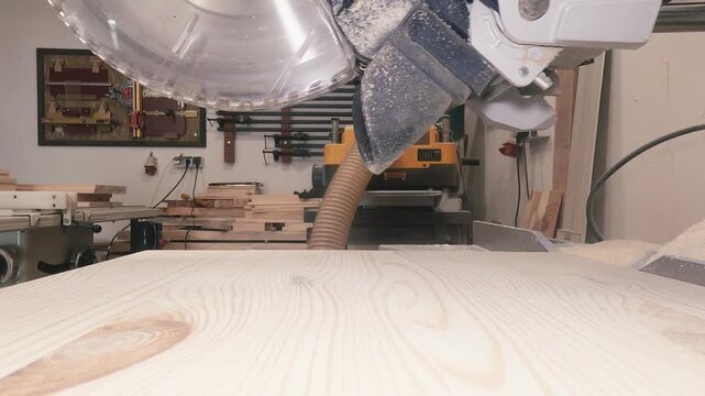 Circular saw cutting wooden board in woodworking workshop, close up industrial manufacturing process